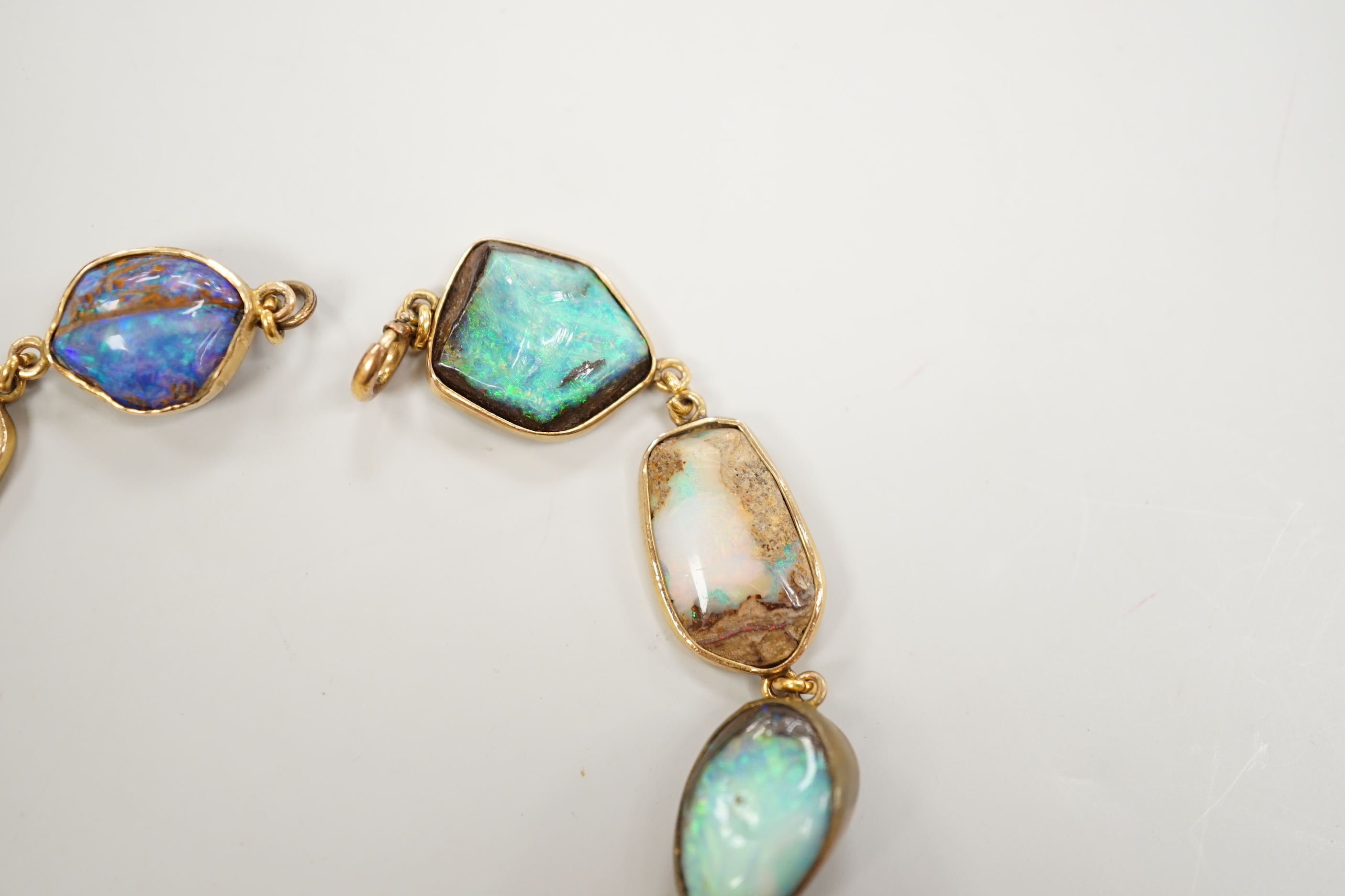 An early 20th century yellow metal and opal set bracelet, of various shapes and hung with central 15ct and diamond chip set charm, 21cm, gross weight 15 grams.